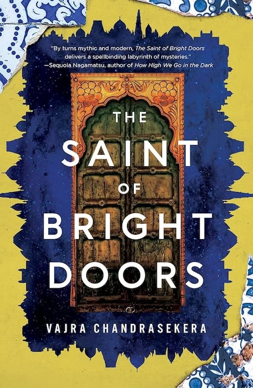 A cover image of Vajra Chandrasekera's novel The Saint of Bright Doors. A wooden door in a South Asian style floats on a blue-black field of stars, surrounded by a yellow border that forms a silhouette of a South Asian city skyline.